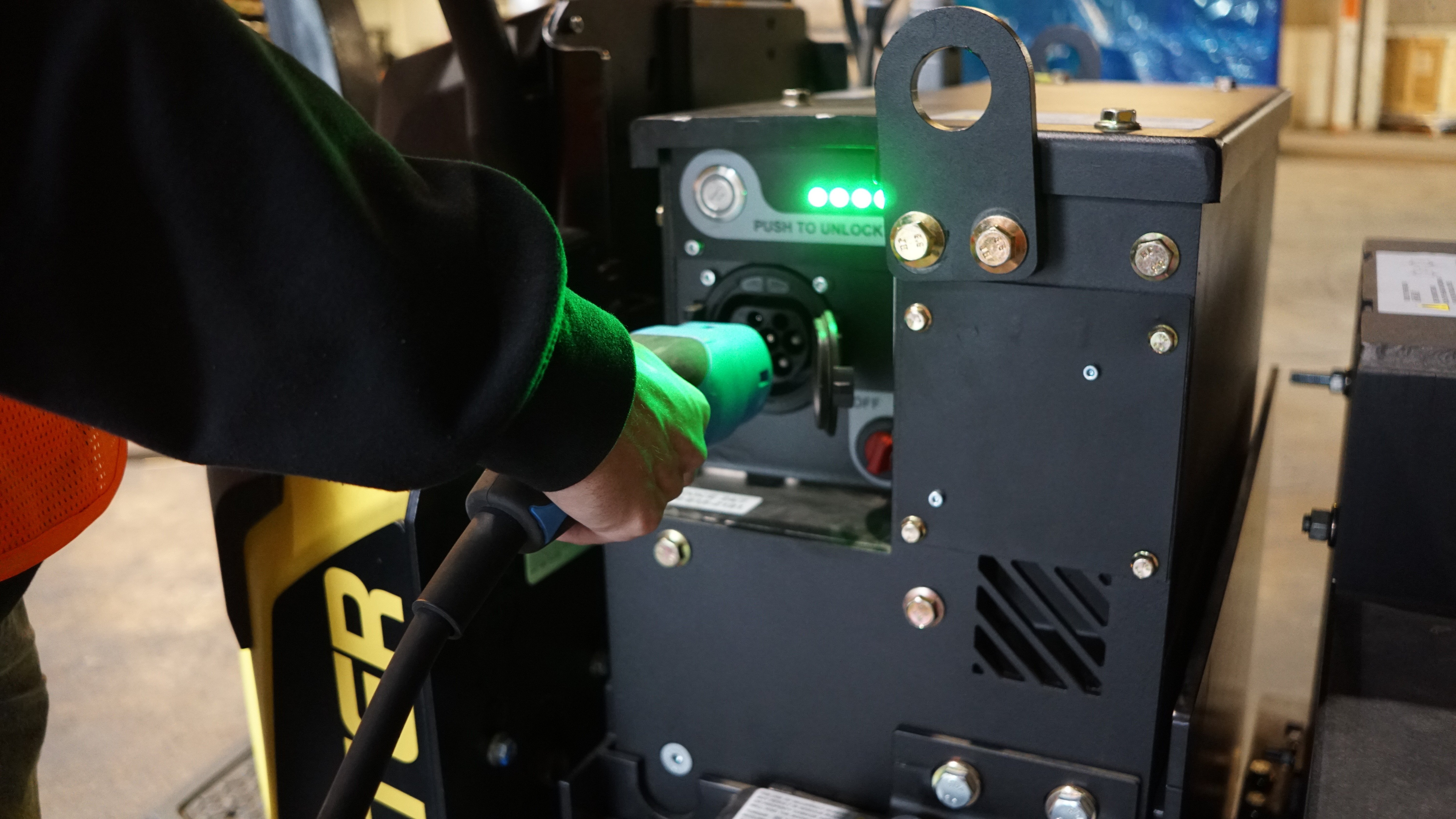 A UgoWork 24V battery being connected to a Hyster pallet jack by an operator